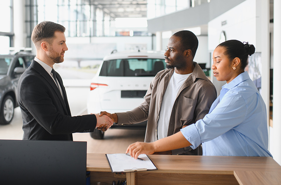 Car dealer shaking hands with a couple